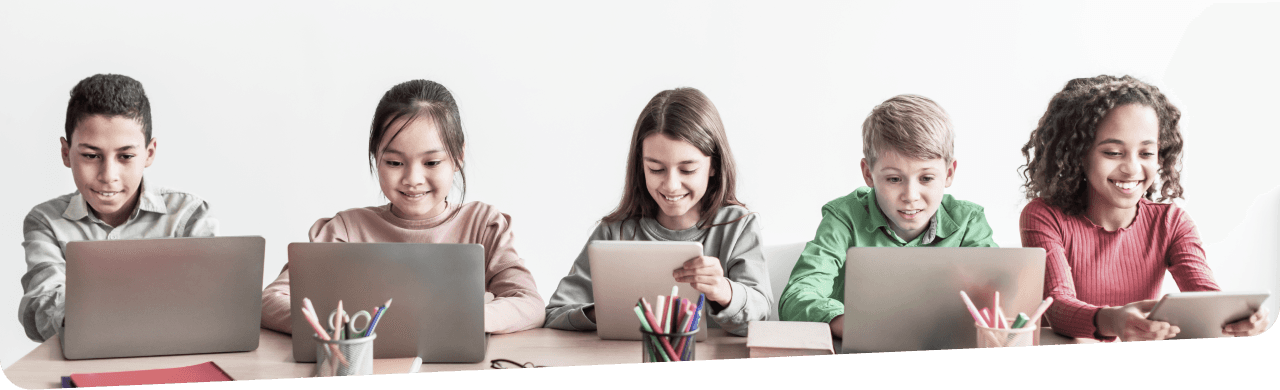 A group of five children sitting right next to each other using their laptops and tablets while in the classroom